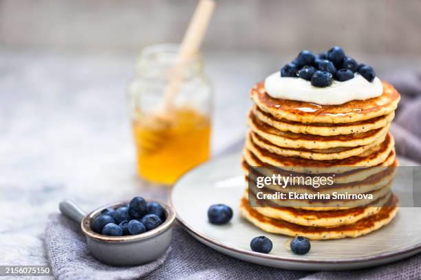 stack of freshly prepared lemon poppy seed pancakes topped with sour cream and blueberries - pancake stock pictures, royalty-free photos & images