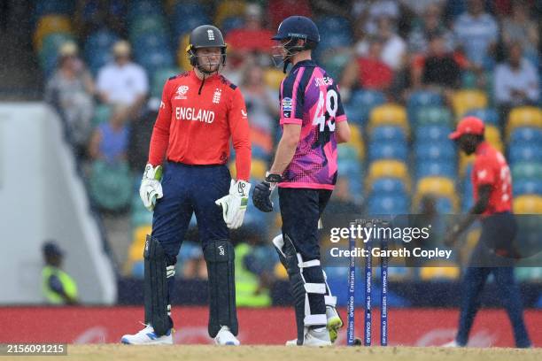 Jos Buttler of England and Michael Jones of Scotland leave the field as rain stops play during the ICC Men's T20 Cricket World Cup West Indies & USA...