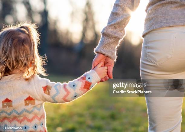 mamá y niña pequeñas tomadas de la mano en un prado - agarrados de la mano fotografías e imágenes de stock