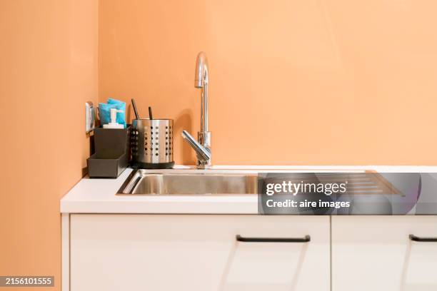 a modern office with a kitchenette featuring a countertop and sink, dining area. - kitchen sink stock pictures, royalty-free photos & images