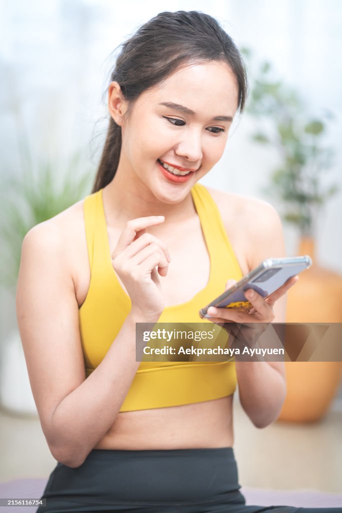 Beautiful, healthy Asian woman wearing sportswear exercising using a smartphone to check her basic health, heartbeat and calories burned after exercising.