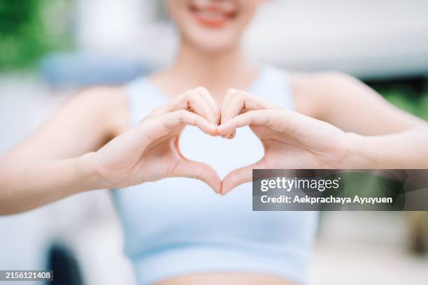 a beautiful, healthy asian woman wearing sportswear makes a heart-shaped gesture, happy from morning healthy exercise. - heart walk stock pictures, royalty-free photos & images