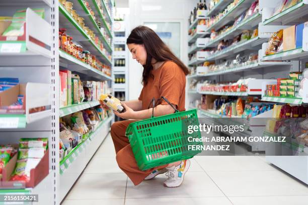 frau kauert in einer supermarktgasse und liest informationen über ein produkt - glutenfrei stock-fotos und bilder