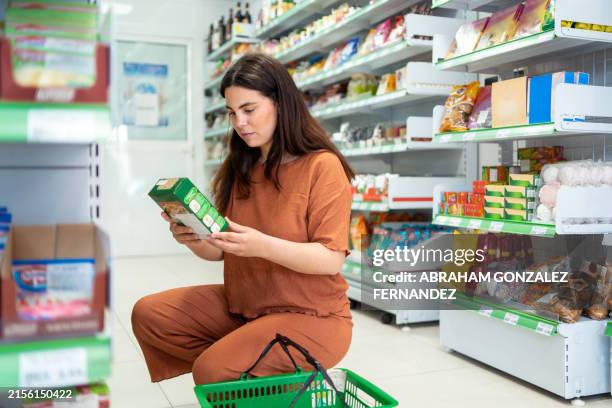 frau liest informationen über die produkte, bevor sie sie im supermarkt kauft - zuckerfrei stock-fotos und bilder
