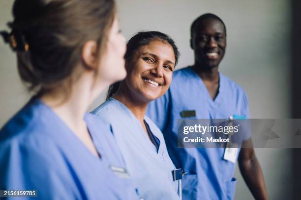 happy multiracial male and female medical professionals in hospital - infermiere foto e immagini stock