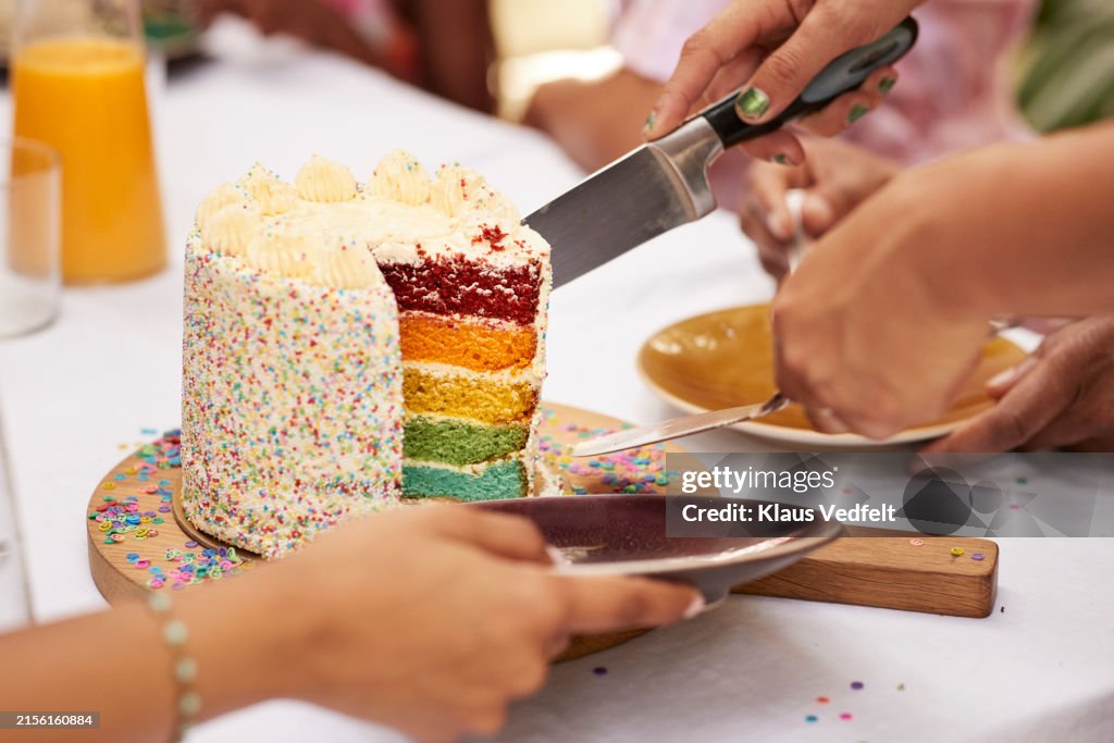 Hands of guests taking birthday cake slice in plate