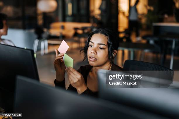 young female entrepreneur reading adhesive notes at office - sticky-notes-covering-computer-monitor stock pictures, royalty-free photos & images
