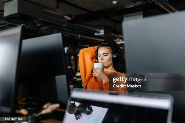 young female computer programmer having coffee during break time at office - programmer computer stock pictures, royalty-free photos & images