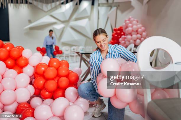 two decorators have blown up many balloons to make decorations for the party - party host stock pictures, royalty-free photos & images