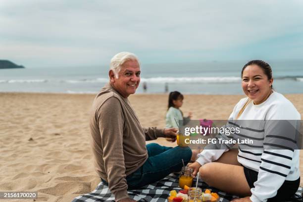 portrait of senior father and daughter in a picnic at beach - fruit juice stock pictures, royalty-free photos & images