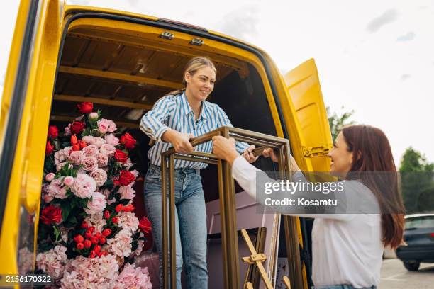 dos organizadores de eventos sacan sillas, arreglos florales, soportes para la decoración del maletero de una furgoneta - organizador de eventos fotografías e imágenes de stock