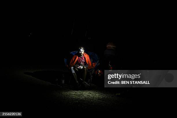 Runner rests at a crew stop at mile 87 on the South Downs Way before sunrise during the Centurion South Downs Way 100 ultramarathon at Firle Bostal...