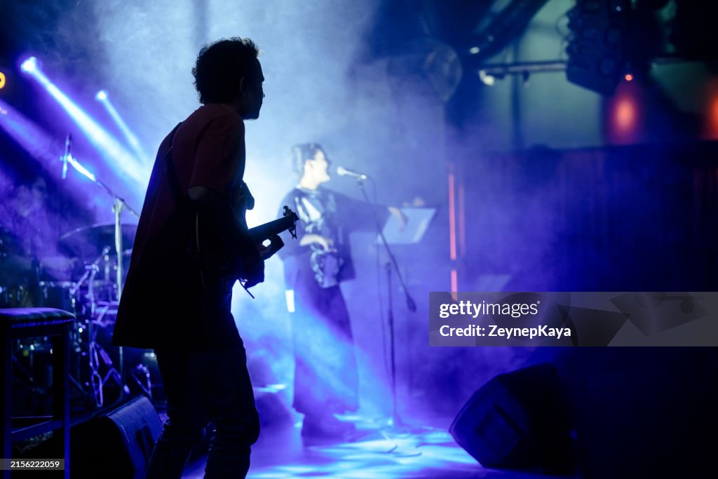 Vocal singer performing on stage with colorful stage lights.