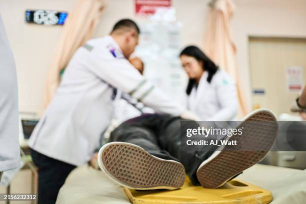 patient lying unconscious in a hospital bed with medical team reviving him - unconscious stock pictures, royalty-free photos & images