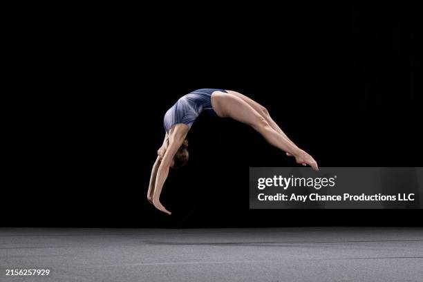 female gymnast performing a somersault during her floor exercise. - vloerturnen stockfoto's en -beelden