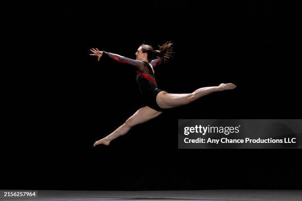 female gymnast performing a jump with the splits during her floor exercise. - gymnast stock pictures, royalty-free photos & images