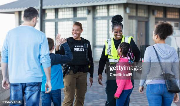 dos mujeres policías saludan a miembros de la comunidad - cuerpo de policía fotografías e imágenes de stock