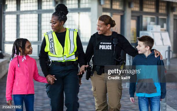two policewomen walking with two children - mulher polícia imagens e fotografias de stock