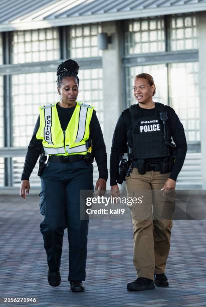 zwei multirassische polizistinnen unterhalten sich auf patrouille - kugelsicher stock-fotos und bilder