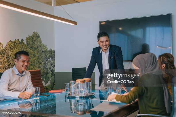 asian young entrepreneur meeting with coworkers in office meeting room. diverse team of creative entrepreneurs at conference table discussion. specialists work in business startup - voorzitter stockfoto's en -beelden