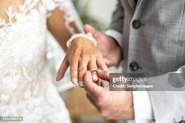 exchanging wedding rings with the groom putting the ring on the finger of his future wife. - cerimonia di nozze foto e immagini stock