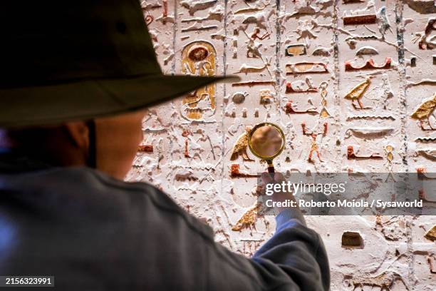 boy examining egyptian hieroglyphics with magnifying glass - archéologie photos et images de collection