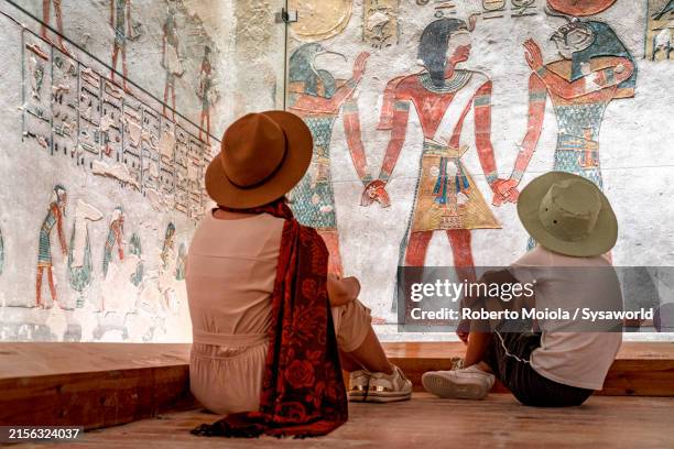 cute boy with mother looking at egyptian wall paintings - pharaoh tomb stock pictures, royalty-free photos & images