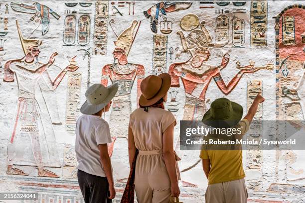 family admiring art inside ramses ix tomb, luxor - registro fotografías e imágenes de stock