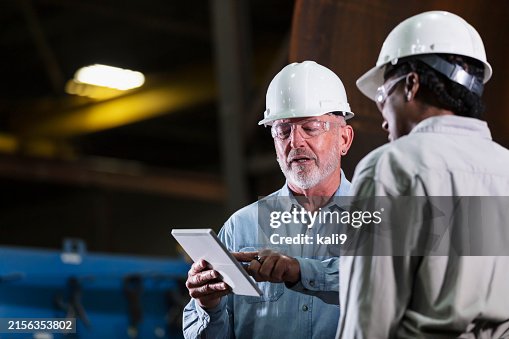 Two workers in warehouse conversing, using digital tablet Two workers in warehouse conversing, using digital tablet