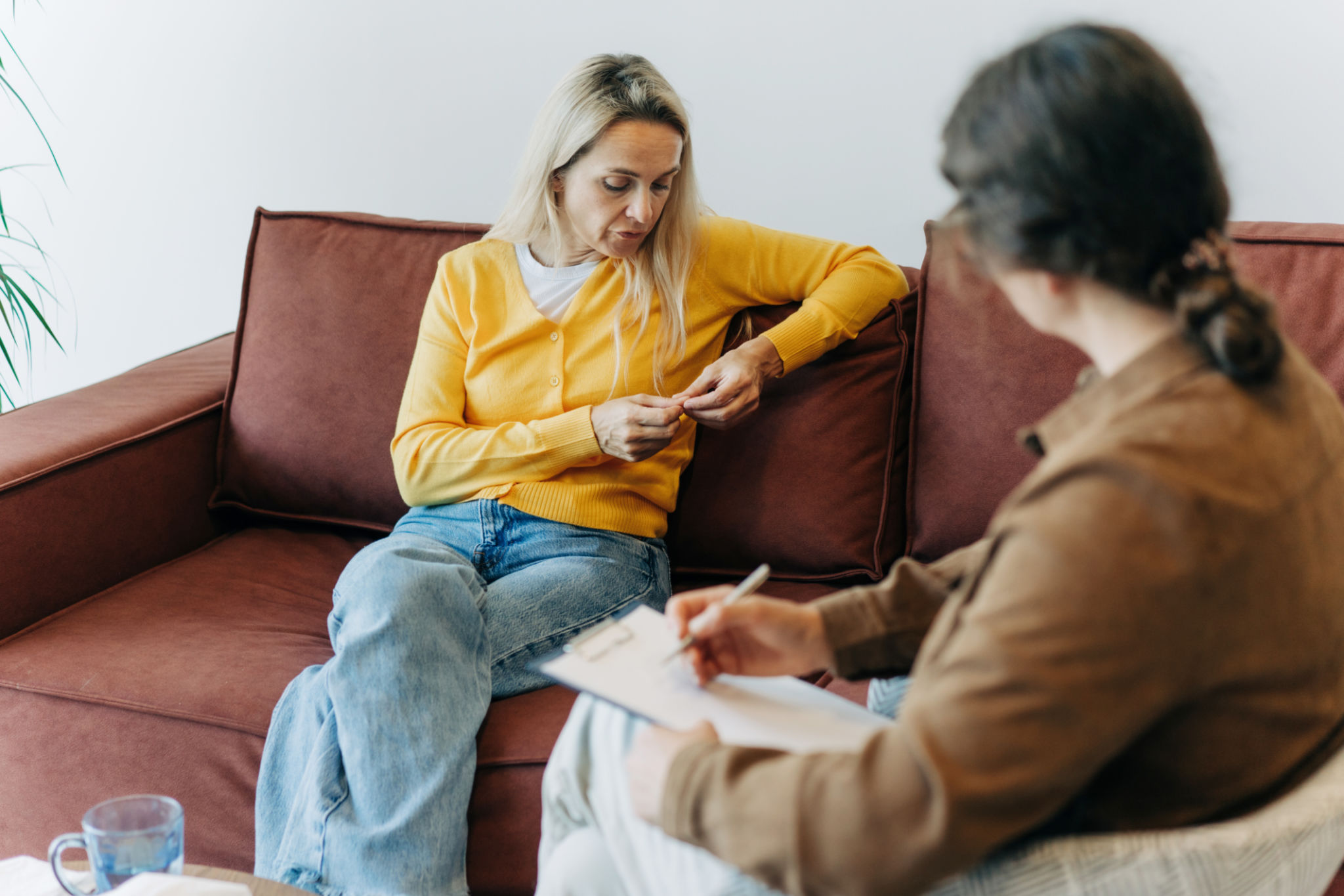 A woman patient, sitting on the couch during a consultation with a psychologist, talks about her difficulties in life, stress and relationship problems. A woman patient, sitting on the couch during a consultation with a psychologist, talks about her difficulties in life, stress and relationship problems.
