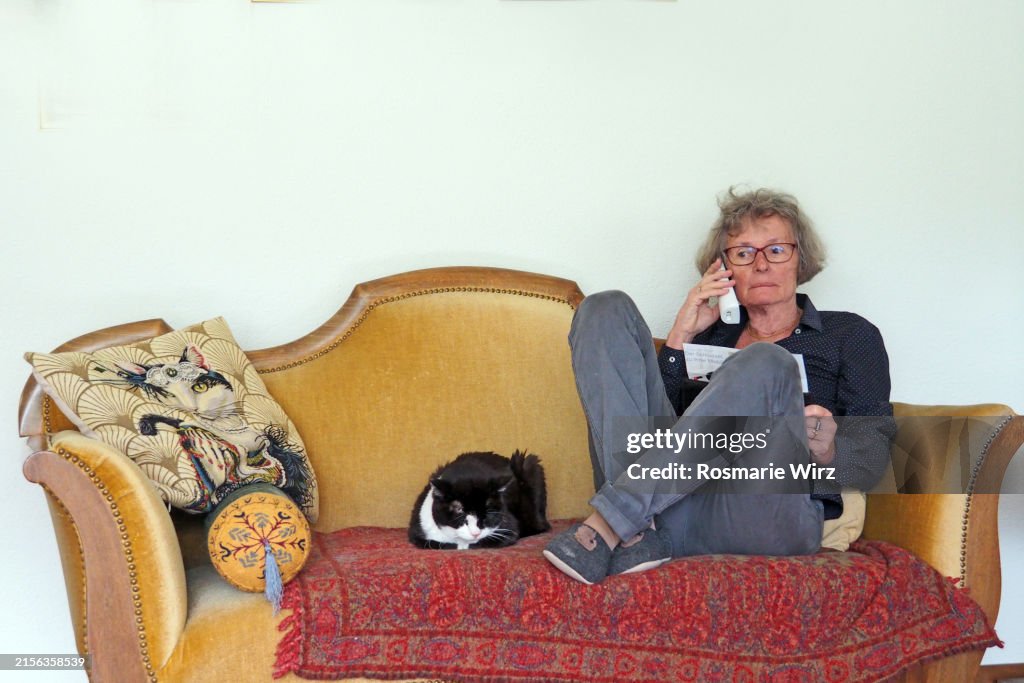 Senior woman on sofa with phone, house cat