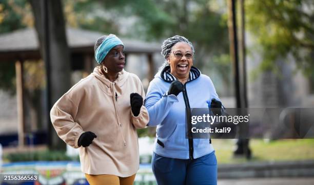 deux femmes âgées noires faisant de l’exercice, marchant rapidement dans un parc - marche sportive photos et images de collection