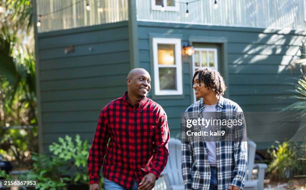 father and teenage son conversing in back yard - father stock pictures, royalty-free photos & images