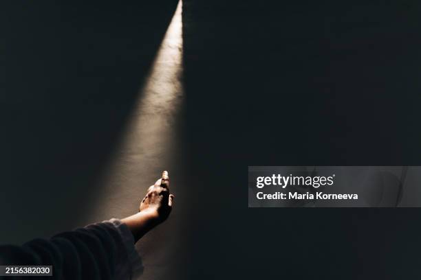 a hand reaches out to the light from above, - paranormal stock pictures, royalty-free photos & images