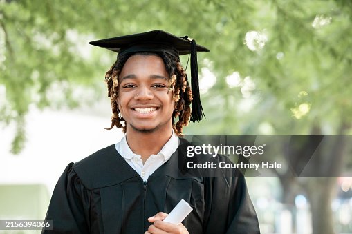 A charming young Black man smiles for the camera at his graduation. A charming young Black man smiles for the camera at his graduation.
