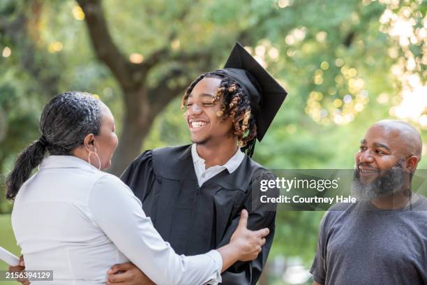 sonriéndole con orgullo a su madre, un joven está de pie con su traje de graduación. - graduación fotografías e imágenes de stock