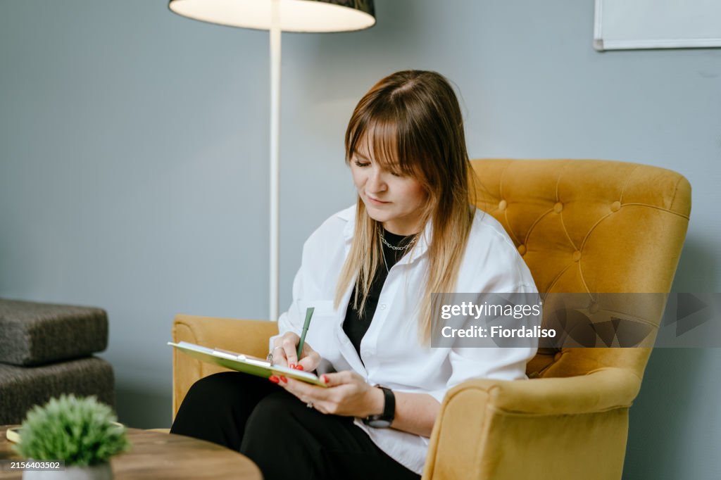 A middle-aged woman sitting in a cozy yellow chair