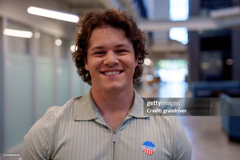Young Man in His Twenties Smiling At Camera Placing an I Voted Sticker on His Shirt in Houston Texas