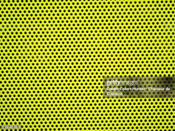 close-up and blur of a metal grid perforated with small holes and painted yellow. sunlight. natural colors. london, england, united kingdom. - metal surface treatment stock pictures, royalty-free photos & images