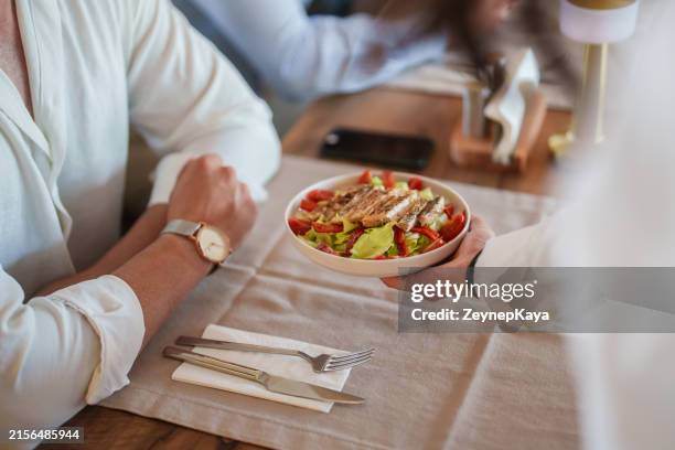 the waitress is serving the plate of food to the table. - serving size stock pictures, royalty-free photos & images