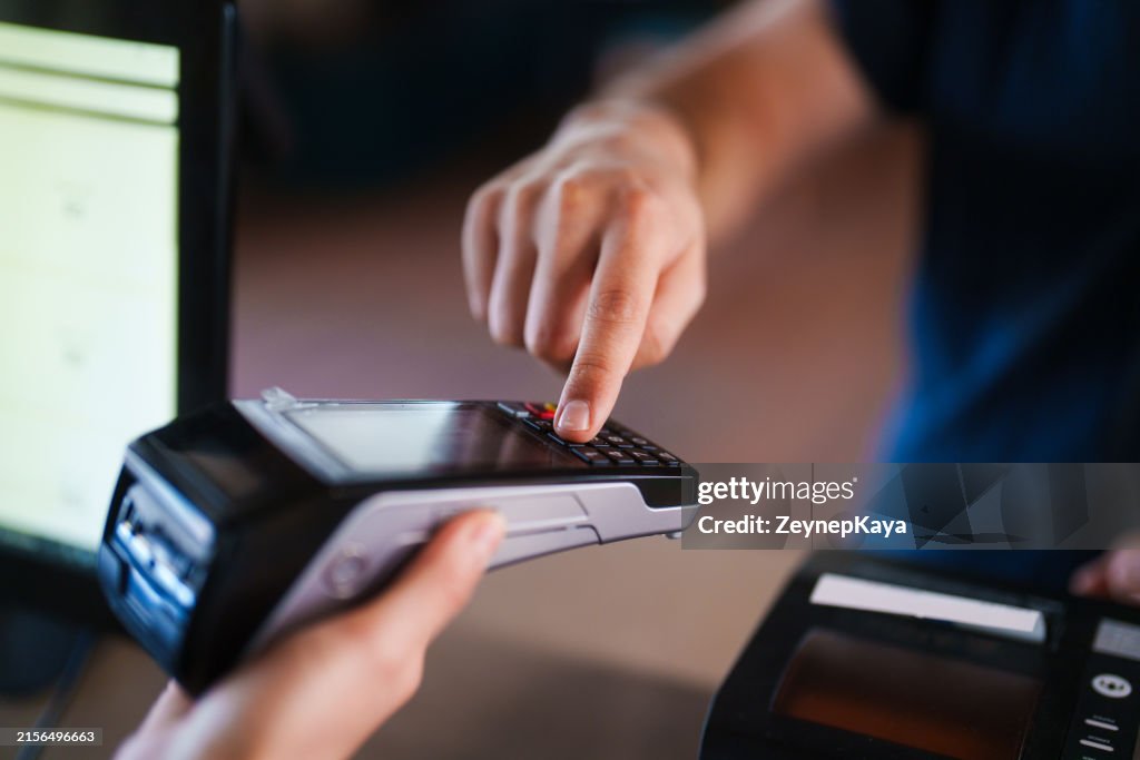 A close-up of a customer entering their PIN code on the POS terminal at the cashier.