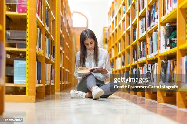 woman reading book sitting on floor in bookstore - cross legged stock pictures, royalty-free photos & images