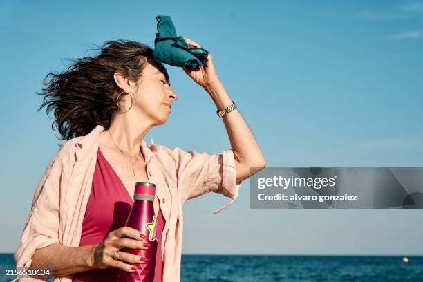 woman in pink swimsuit experiencing heatwave at the beach - climate change - só uma mulher idosa imagens e fotografias de stock