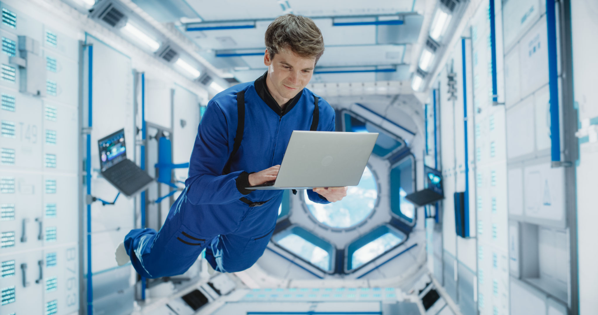 Caucasian Male Astronaut Using a Laptop to Wirelessly Connect to a Satellite. Scientist Working on Computer Device Inside an Intergalactic Station. Professional Engineer Undertaking Online Service Job Caucasian Male Astronaut Using a Laptop to Wirelessly Connect to a Satellite. Scientist Working on Computer Device Inside an Intergalactic Station. Professional Engineer Undertaking Online Service Job