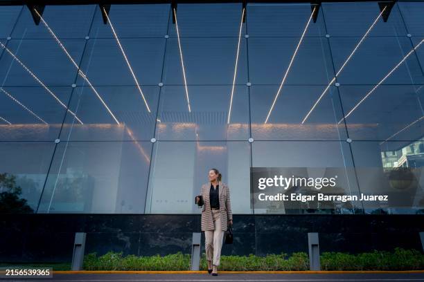 business woman walking in front of a corporate building. - mexico city building stock pictures, royalty-free photos & images