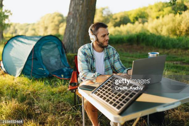 man working on laptop near camping tent - battery life stock pictures, royalty-free photos & images