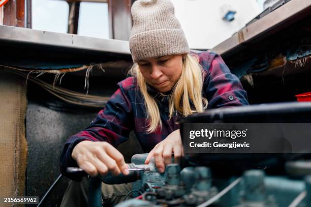 una mujer realizando el mantenimiento del motor de un barco - motor eléctrico fotografías e imágenes de stock