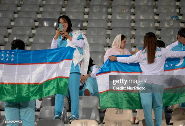 Female Uzbek fans are holding Uzbekistan's flag during the FIFA World Cup 26 AFC qualifying round two group E soccer match between Iran and...
