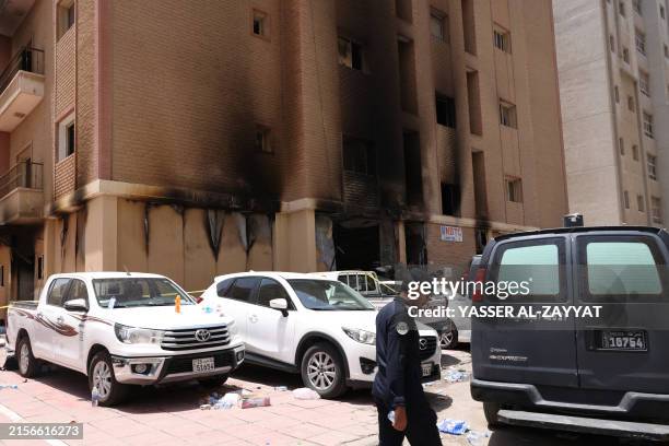 Member of the Kuwaiti security forces stand outside a building which was ingulfed by fire, in Kuwait City, on June 12, 2024. More than 35 people were...