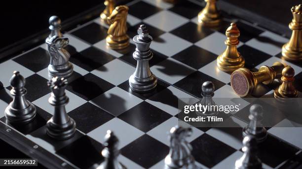 intense chess match with gold and silver pieces - schach stock-fotos und bilder